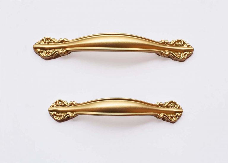 Mâner modern de mobilier din aluminiu auriu, prezentat pe fundal deschis.