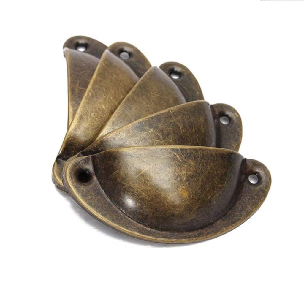 Mâner tip scoică din metal cu finisaj bronz, fotografiat pe fundal deschis.